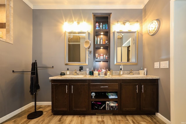 full bath with crown molding, wood finished floors, double vanity, and a sink