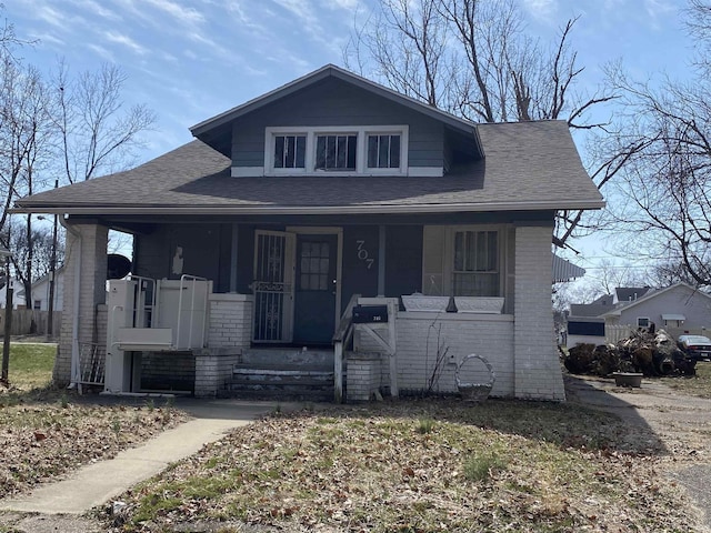 bungalow featuring brick siding, a porch, and a shingled roof