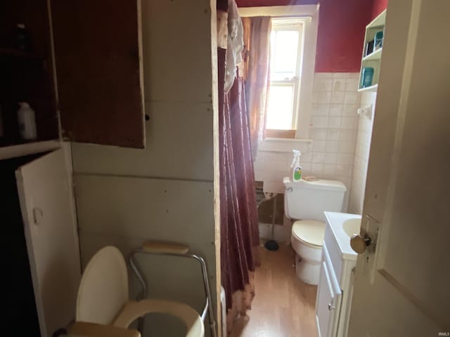 full bathroom with tile walls, a wainscoted wall, toilet, a shower with curtain, and vanity