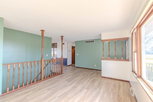 empty room featuring visible vents, baseboards, and wood finished floors