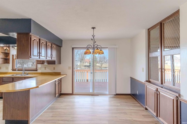 kitchen with a peninsula, light wood-style floors, light countertops, and a sink