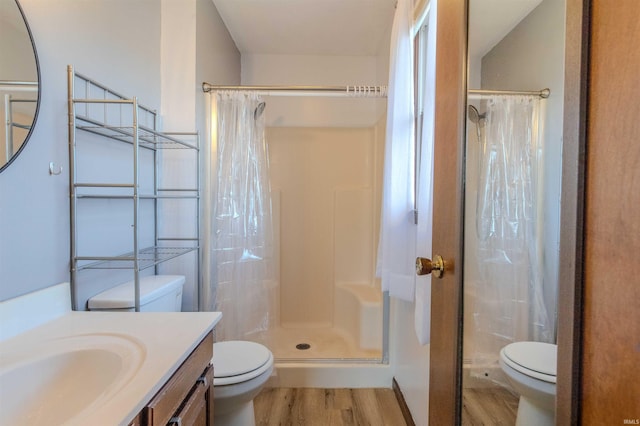 bathroom with vanity, a shower stall, toilet, and wood finished floors