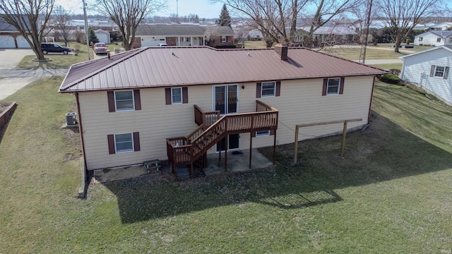 rear view of property featuring stairs, a deck, a lawn, and metal roof