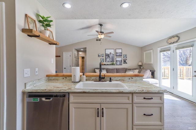 kitchen with a sink, open shelves, stainless steel dishwasher, open floor plan, and vaulted ceiling