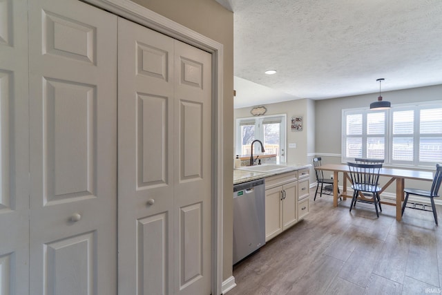 kitchen featuring a sink, light countertops, a textured ceiling, dishwasher, and light wood-type flooring