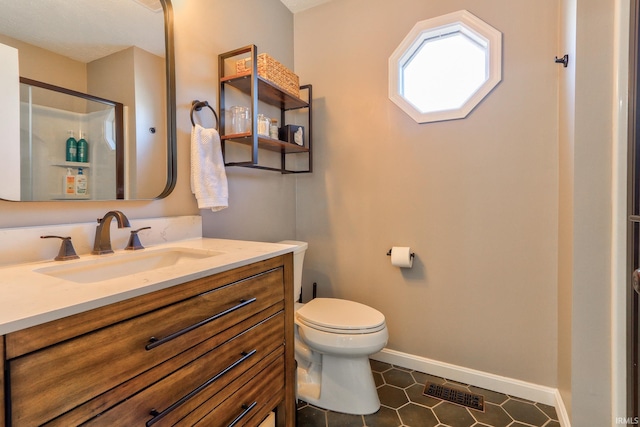 bathroom with vanity, baseboards, visible vents, a stall shower, and toilet