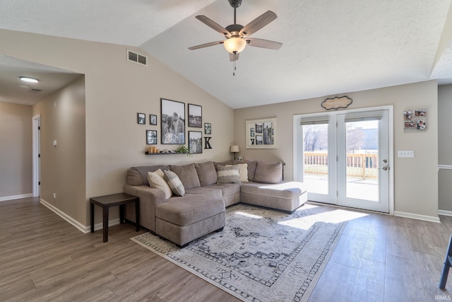 living area with visible vents, baseboards, vaulted ceiling, wood finished floors, and a ceiling fan