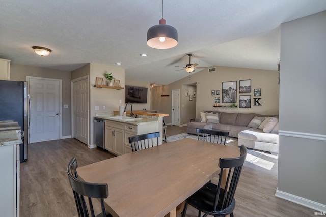 dining room featuring wood finished floors, baseboards, visible vents, lofted ceiling, and ceiling fan