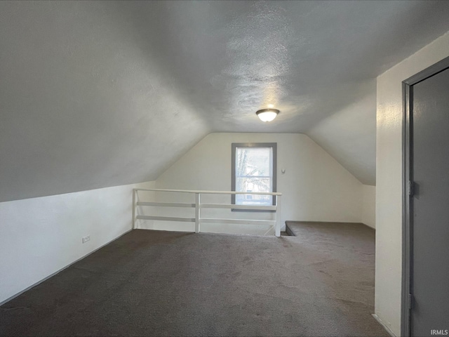 bonus room featuring dark carpet, a textured ceiling, and lofted ceiling