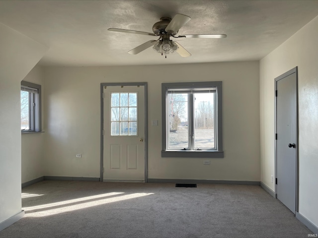 foyer with plenty of natural light, visible vents, baseboards, and carpet