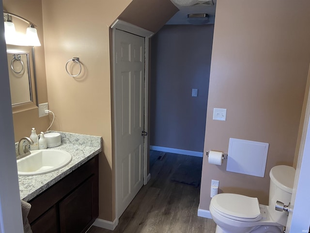 bathroom featuring vanity, toilet, wood finished floors, and baseboards