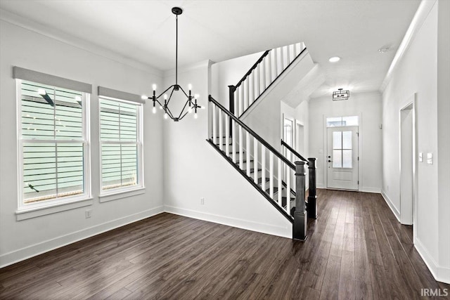 foyer entrance with ornamental molding, dark wood finished floors, stairway, an inviting chandelier, and baseboards