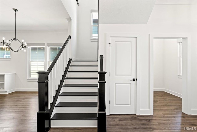 staircase featuring a notable chandelier, baseboards, and wood finished floors