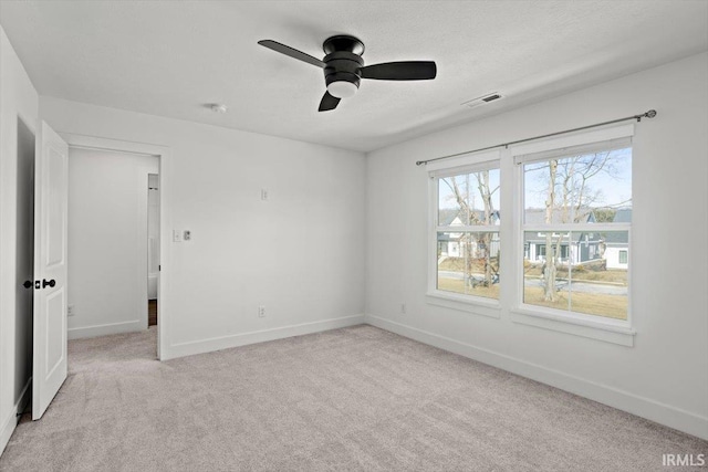 unfurnished room featuring visible vents, light colored carpet, baseboards, and ceiling fan