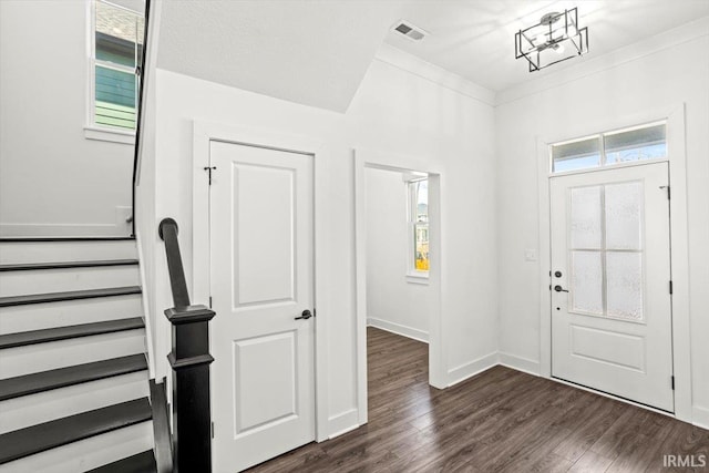 foyer entrance with baseboards, visible vents, dark wood-style flooring, ornamental molding, and stairs