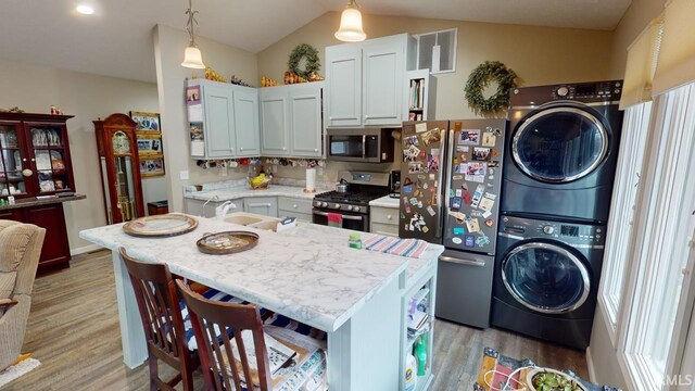 kitchen featuring a sink, stainless steel appliances, stacked washer and dryer, and light wood finished floors