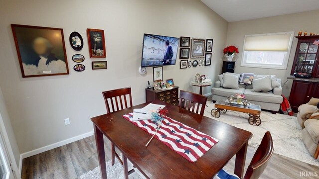 dining space featuring baseboards, lofted ceiling, and wood finished floors