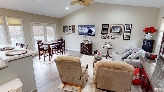 living room with lofted ceiling, baseboards, light wood-type flooring, and ceiling fan