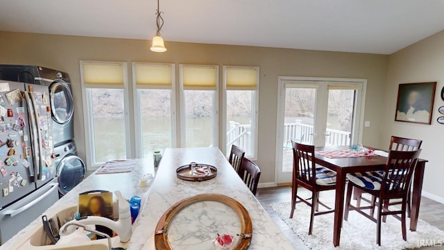 dining area featuring light wood-style flooring, french doors, baseboards, and stacked washer and dryer