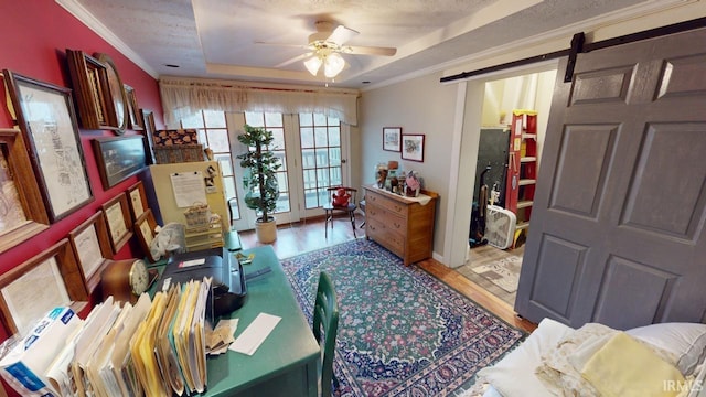 home office featuring a tray ceiling, crown molding, a barn door, and wood finished floors