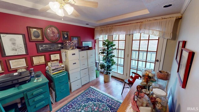 office area with ceiling fan, a raised ceiling, light wood-type flooring, and ornamental molding