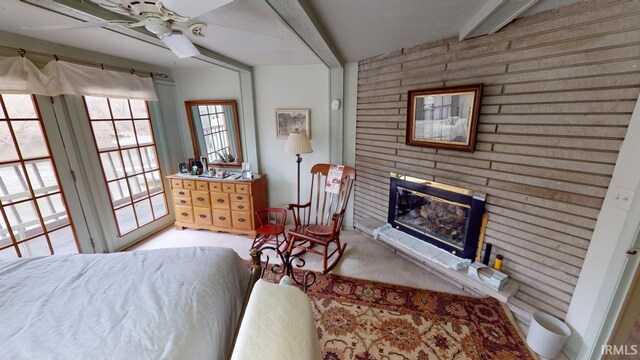 carpeted bedroom with beam ceiling and a brick fireplace