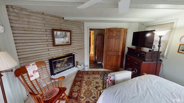 carpeted bedroom featuring beamed ceiling, a brick fireplace, and a ceiling fan