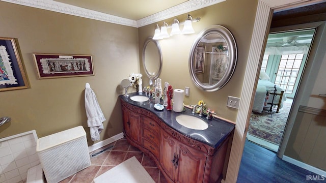 bathroom with double vanity, baseboards, visible vents, and a sink