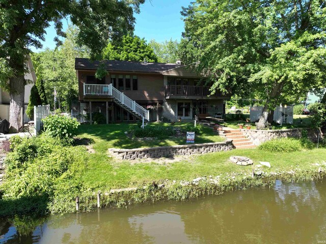 rear view of property with stairway, a yard, and a deck with water view