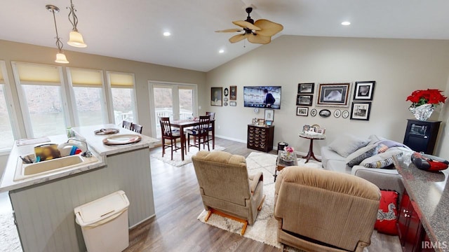 living area with wood finished floors, recessed lighting, baseboards, ceiling fan, and vaulted ceiling