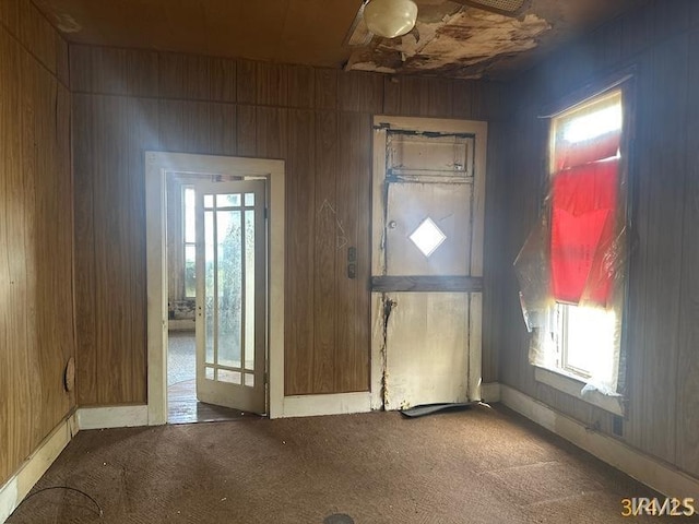 carpeted entryway with wooden walls