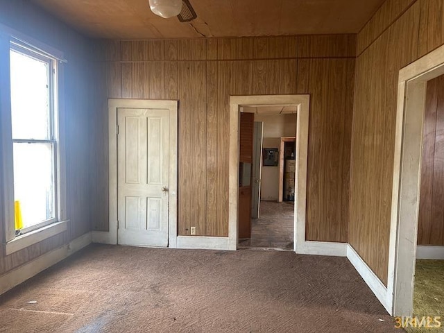 unfurnished bedroom featuring carpet flooring and wood walls