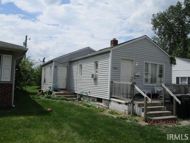 back of house featuring entry steps, a yard, and a chimney