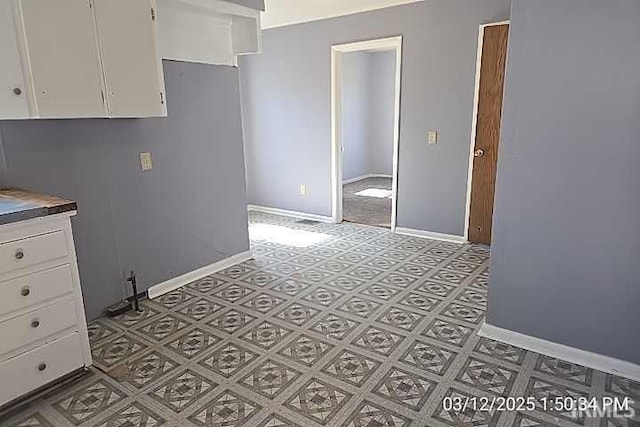 interior space featuring baseboards and white cabinets