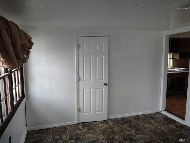 unfurnished room featuring baseboards and stone finish flooring