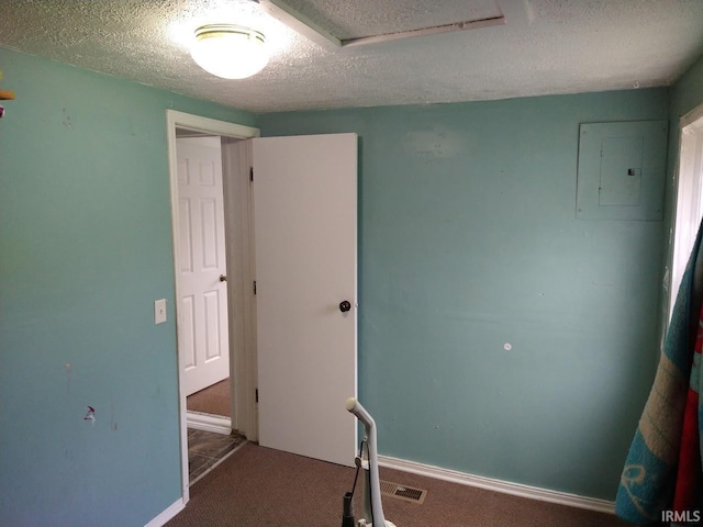 carpeted spare room with electric panel, visible vents, a textured ceiling, and baseboards