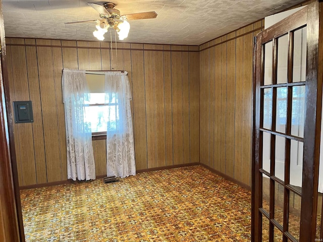 spare room with baseboards, wooden walls, and ceiling fan