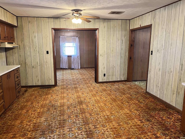 interior space featuring visible vents, baseboards, wooden walls, and ceiling fan