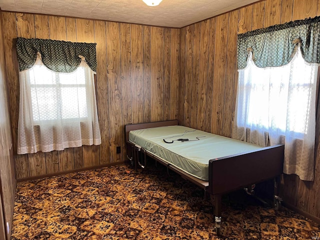 carpeted bedroom with baseboards and wood walls