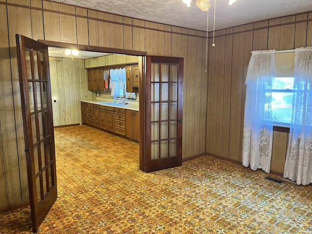 kitchen with visible vents, wood walls, light countertops, brown cabinets, and a sink