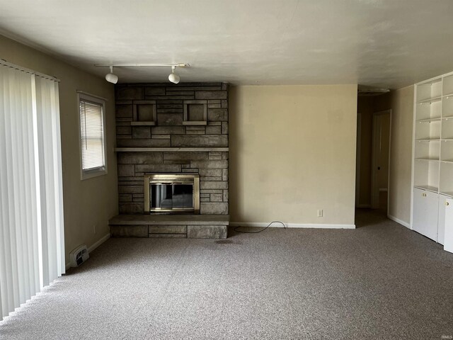 unfurnished living room with baseboards, a stone fireplace, and carpet flooring