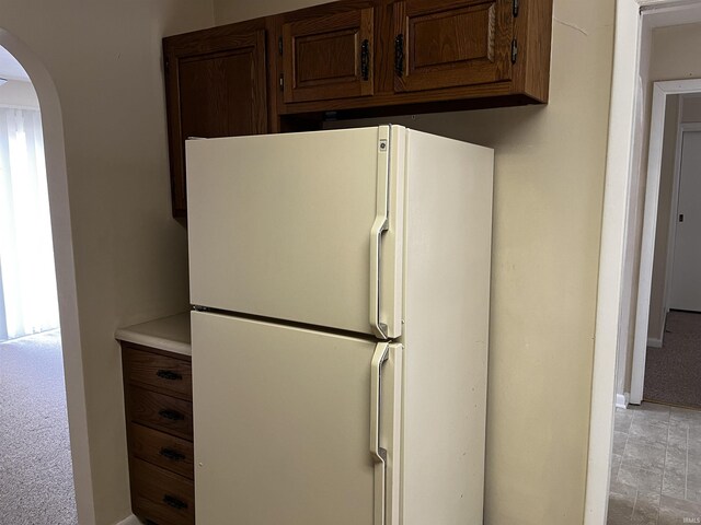 kitchen featuring arched walkways, light countertops, and freestanding refrigerator