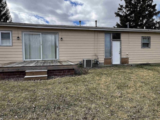 rear view of property with a deck, a yard, and central AC