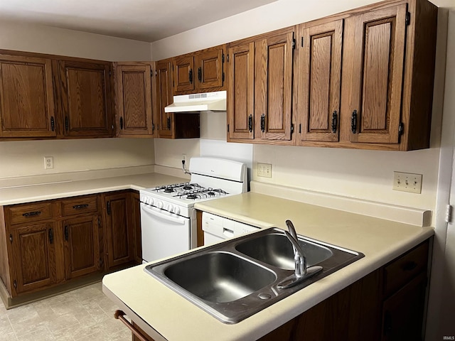 kitchen featuring under cabinet range hood, white gas range, light countertops, and a sink