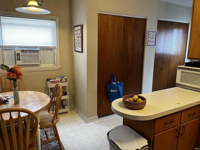 dining room featuring cooling unit, light floors, and baseboards