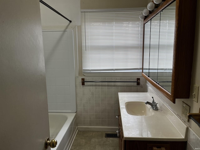 full bath with vanity, tile walls, and bathtub / shower combination