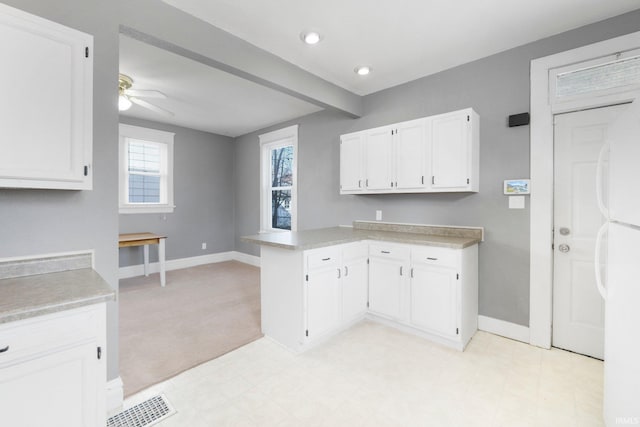 kitchen with white cabinetry, a peninsula, light countertops, and visible vents