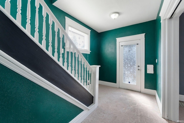 carpeted foyer entrance with stairway and baseboards