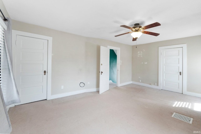 unfurnished bedroom featuring visible vents, baseboards, light colored carpet, and ceiling fan