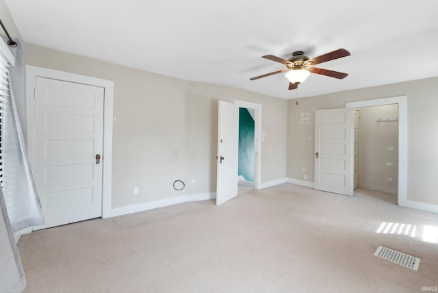 unfurnished bedroom with visible vents, light carpet, baseboards, and a ceiling fan